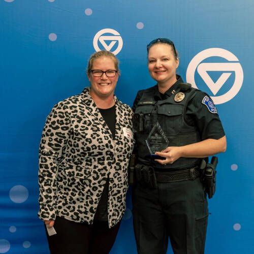 Kelli Dykstra at left with police Capt. Leah Heaton in uniform and she is holding a glass award